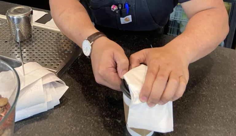 barista placing lid on coffee